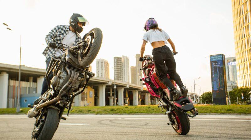 man and woman riding on motorbikes doing stunt